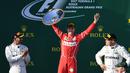 Pembalap Ferrari, Sebastian Vettel berpose dengan trofinya setelah memenangi balapan GP Australia di Sirkuit Albert Park, Melbourne, Minggu (26/3). Pembalap asal Jerman tersebut sukses mengalahkan pesaing terberatnya Lewis Hamilton. (WILLIAM WEST/AFP)