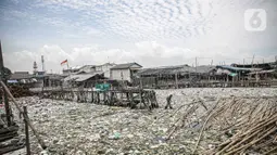 Suasana jembatan kayu di antara sampah di perkampungan nelayan Cilincing, Jakarta, Minggu (21/2/2022). Peringatan HPSN 2022, Pemprov DKI Jakarta mengajak warga Jakarta untuk peduli sampah mulai dari lingkungan terdekat minimal dengan cara memilah sampah dari rumah. (Liputan6.com/Faizal Fanani)