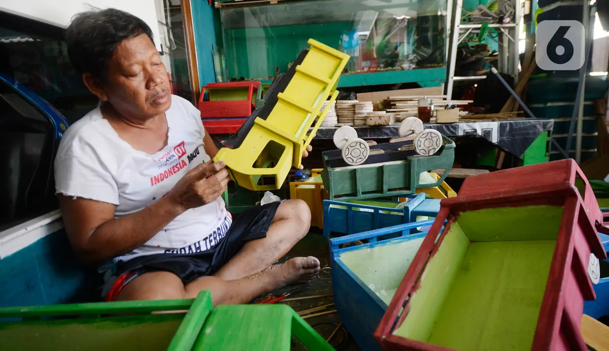 Perajin Uus Saputra (58) menyelesaikan mobil mainan dari limbah kayu bekas di Kelurahan Ciputat, Tangerang Selatan, Banten, Rabu (28/10/2020). Mobil mainan yang menggunakan bahan baku kayu tersebut dijual seharga Rp 50 ribu hingga Rp 250 ribu tergantung ukuran. (merdeka.com/Dwi Narwoko)