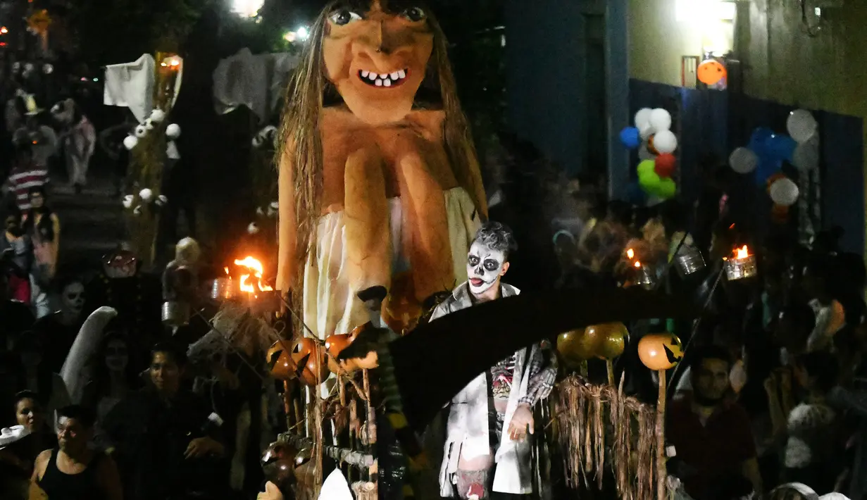 Sejumlah peserta mengenakan kostum dan membawa patung hantu menggelar pawai dalam parade La Calabiuza di Tonacatepeque, El Salvador (1/11). Parade tersebut untuk memperingati Hari Orang Mati. (AFP Photo/Marvin Recinos)