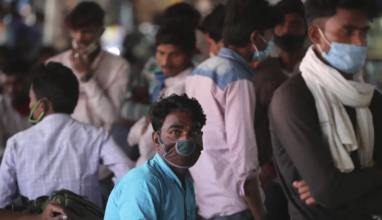 Buruh migran yang memakai masker sebagai antisipasi terhadap virus corona menunggu pengangkutan di terminal bus di Jammu, India(26/3/2021). Pihak berwenang di kota Mumbai mengatakan mereka akan menggelar tes virus korona acak wajib di tempat-tempat ramai. (AP Photo/Channi Anand)