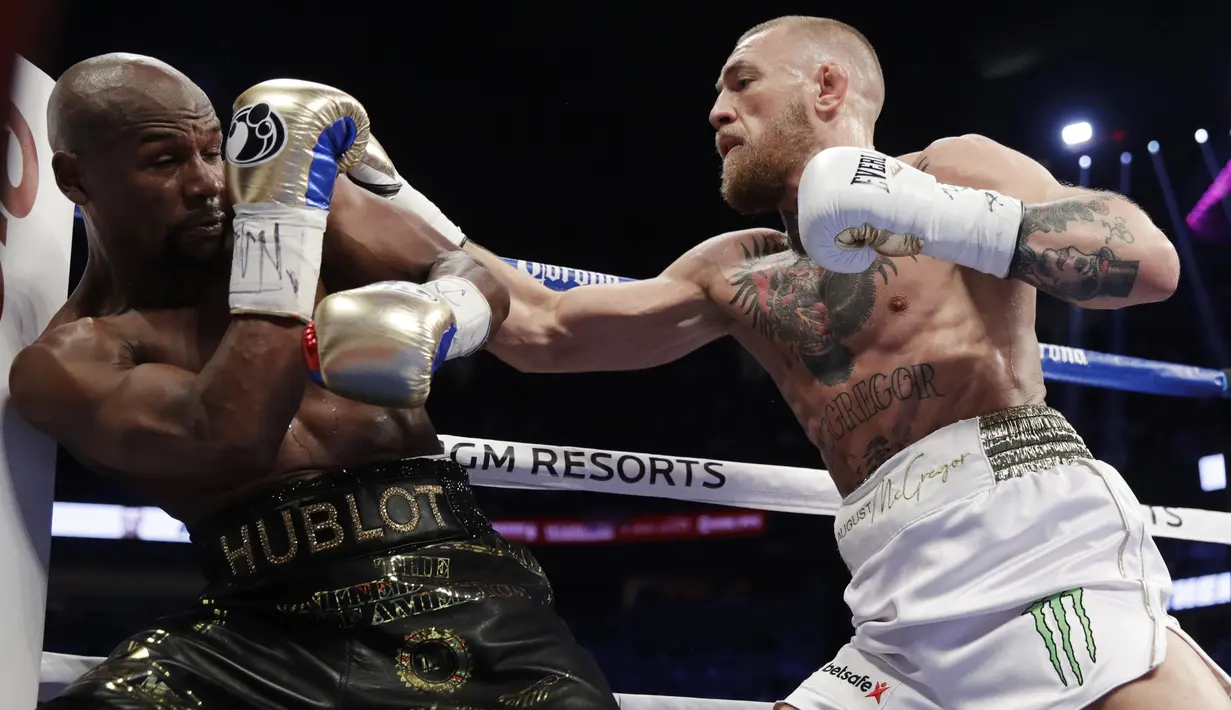 Serangan Conor McGregor (kanan) yang mampu diblok Floyd Mayweather Jr. pada gelaran Tinju Dunia super welterweight boxing di MGM Arena, Las Vegas, (26/8/2017). Mayweather menang TKO atas McGregor. (AP/Isaac Brekken)