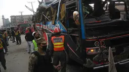 Polisi melakukan penyelidikan di sekitar badan bus usai diserang bom di Peshawar, Pakistan, Rabu (16/3). Bus yang membawa rombongan pegawai pemerintah ini menewaskan setidaknya 10 orang dan 27 lainnya terluka. (AFP / A Majeed)