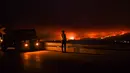 Seorang pria berdiri di pinggir jalan melihat kebakaran hutan di Anciao, Portugal tengah, Minggu (18/6). Kebakaran hutan terjadi pada sore hari di kotamadya Pedrogao Grande sebelum menyebar dengan cepat di beberapa bidang. (PATRICIA DE MELO MOREIRA/AFP)