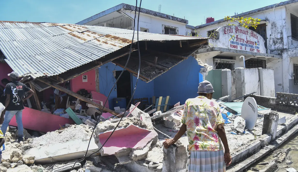 Seorang perempuan berdiri di depan rumah yang hancur setelah gempa bumi di Les Cayes, Haiti, Sabtu (14/8/2021). Wilayah Negara Haiti diguncang gempa berkekuatan magnitudo 7,1 pada Sabtu, 14 Agustus 2021 pukul 08.29.10 waktu setempat yang menewaskan lebih dari 300 jiwa. (AP Photo/Duples Plymouth)