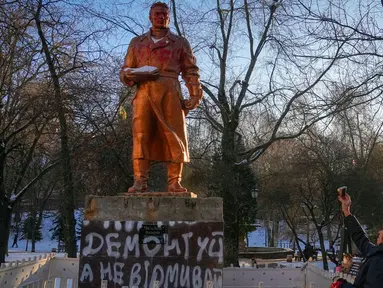 Seorang wanita mengambil foto monumen era Soviet untuk pilot Rusia Valery Chkalov sebelum pembongkaran monumen tersebut di Kyiv, Ukraina, 8 Februari 2023. Ukraina mempercepat upaya untuk menghapus sisa-sisa pengaruh Soviet dan Rusia selama berabad-abad dari ruang publik dengan merobohkan monumen dan mengganti nama ratusan jalan untuk menghormati seniman, penyair, kepala militer, dan pemimpin kemerdekaan yang tumbuh di dalam negeri. (AP Photo/Efrem Lukatsky)