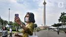 Warga berswafoto saat berkunjung pada hari perdana uji coba pembukaan Monumen Nasional (Monas), Jakarta Pusat, Kamis (16/6/2022). Pasca ditutup sejak 2020 akibat pandemi Covid-19, Pemprov DKI Jakarta melakukan uji coba pembukaan kawasan wisata Monas secara bertahap dan terbatas yang dimulai dari kawasan luar tugu. (merdeka.com/Iqbal S Nugroho)