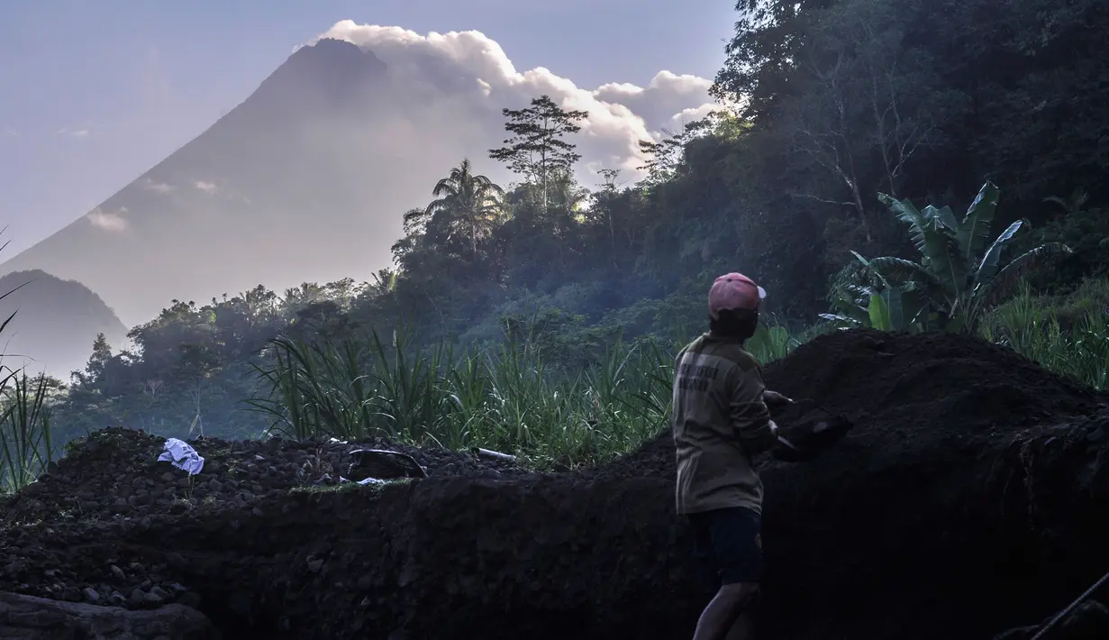 Seorang pria bekerja di lokasi penambangan pasir saat Gunung Merapi mengeluarkan abu vulkanik di Yogyakarta, Indonesia, (22/5).  Pihak berwenang juga memerintahkan warga dalam jarak 3 kilometer (2 mil) untuk mengungsi. (AP Photo/Slamet Riyadi)