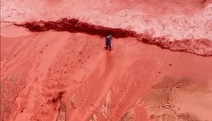 Gambar yang diambil dari rekaman video ini memperlihatkan bagaimana hujan untuk sementara mengubah garis pantai Pantai Merah yang terkenal di Pulau Hormuz, Iran, menjadi pemandangan alam yang mencolok pada Selasa (16/12/2025). (Dok. AP)