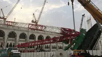 Pekerja dibantu alat berat berusaha mengevakuasi crane yang roboh di Masjidil  Haram, Kota Mekah,  Arab Saudi (9/12/2015). Sebanyak 107 calon jemaah haji meninggal dunia akibat crane jatuh karena cuaca buruk. (AFP PHOTO / STR)