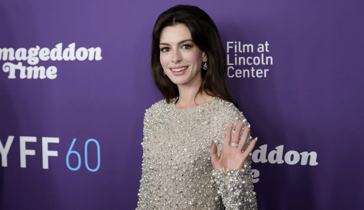 Anne Hathaway melambaikan tangan saat tiba menghadiri pemutaran perdana film "Armageddon Time" selama Festival Film New York ke-60 di Alice Tully Hall  di New York pada Rabu, 12 Oktober 2022. Anne mengenakan sepasang anting-anting perak yang menjuntai dan melapisi kulitnya dengan sedikit sentuhan blush on pink, eye shadow yang mempesona, dan liner untuk menonjolkan mata cokelatnya. (Photo by Charles Sykes/Invision/AP)