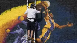 Seniman melukis mural peringatan untuk legenda NBA Kobe Bryant, yang tewas bersama putrinya Gianna dalam kecelakaan helikopter, di Hollywood Barat, California (30/1/2020). Kobe menghabiskan kariernya selama 20 tahun bersama  Los Angeles Lakers. (AFP/Mark Ralston)