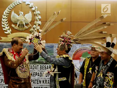 Wakil Ketua DPD Nono Sampono (kedua kiri) menerima pakaian adat untuk prajurit dari Tokoh Adat Dayak di Kompleks Parlemen Senayan, Jakarta, Selasa (19/9). (Liputan6.com/Johan Tallo)