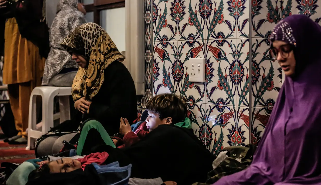 Seorang anak laki-laki bermain telepon ketika ibunya dan para wanita Muslim lainnya berdoa pada malam pertama salat tarawih di Masjid Nizamiye di Midrand, Johannesburg, Afrika Selatan (16/5). (AFP Photo/Gulshan Khan)
