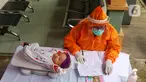 Bidan mengenakan alat pelindung diri (APD) saat melakukan imunisasi kepada bayi di Puskesmas Karawaci Baru, Tangerang, Banten, Rabu (13/5/2020). Pelayanan imunisai sesuai jadwal ini diberikan kepada bayi untuk menambah kekebalan imun tubuh. (Liputan6.com/Angga Yuniar)