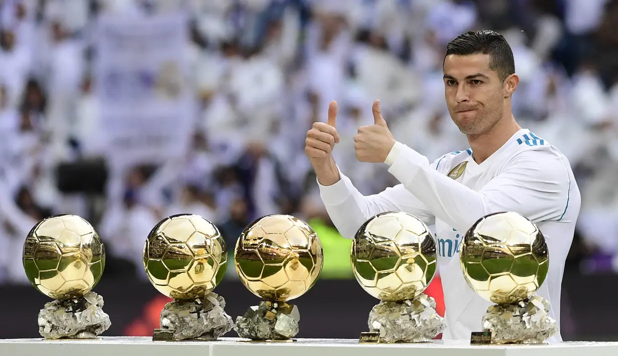 Bintang Real Madrid, Cristiano Ronaldo, berpose dengan kelima trofi Ballon d'Or di Stadion Santiago Bernabeu, Sabtu (9/12/2017). Cristiano Ronaldo meraih Ballon d'Or 2017 setelah unggul dari Lionel Messi dan Neymar. (AFP/Pierre-Philippe Marcou)