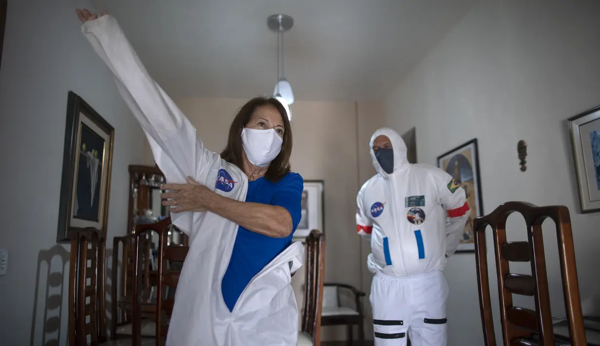 Akuntan Brasil Tercio Galdino (66) dan istrinya Alicea Galdino mengenakan pakaian pelindung mirip astronaut saat akan pergi ke Pantai Copacabana Rio de Janeiro, Brasil, 12 Juli 2020. Tercio membuat pakaian pelindung tersebut untuk melindungi dirinya dan sang istri dari COVID-19. (Mauro Pimentel/AFP)