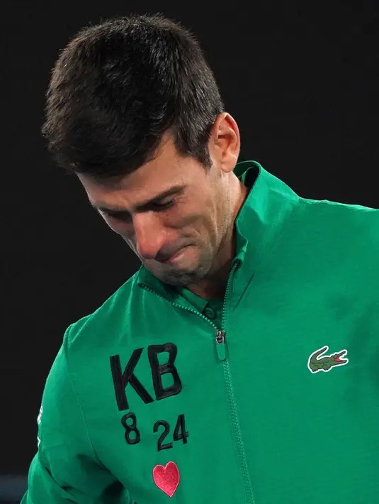 Reaksi Novak Djokovic saat diwawancarai tentang kematian Kobe Bryant usai mengalahkan Milos Raonic pada perempat final Australia Terbuka di Melbourne, Selasa (28/1/2020). Djokovic mengenakan jaket dengan inisial dan nomor punggung Kobe Bryant untuk menghormati temannya itu. (AP Photo/Lee Jin-man)