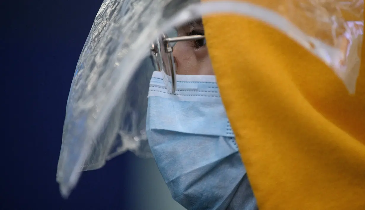 Penumpang memakai masker dan pelindung plastik darurat sebagai tindakan pencegahan terhadap virus corona COVID-19 setelah mendarat di bandara internasional Hong Kong (19/3/2020). Covid-19 yang menginfeksi lebih dari 200.000 orang terus menimbulkan kekhawatiran. (AFP/Anthony Wallace)