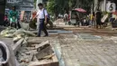 Pejalan kaki melintasi trotoar yang sedang direvitalisasi di kawasan Kramat Raya, Jakarta, Rabu (6/11/2019). Revitalisasi trotoar menyebabkan para pejalan kaki harus berjalan di pinggir jalan dan bersinggungan dengan sepeda motor. (Liputan6.com/Faizal Fanani)