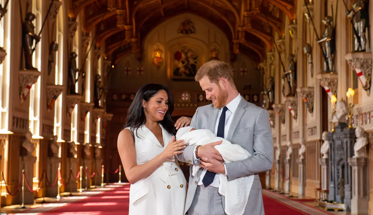 Pangeran Harry dan Meghan Markle berpose dengan bayi laki-lakinya yang baru lahir di St George's Hall di Windsor Castle di Windsor, London (8/5/2019). Pangeran Harry menyatakan bahwa dia dan Meghan Markle masih memikirkan nama anak mereka. (AFP Photo/Dominic Lipinski)