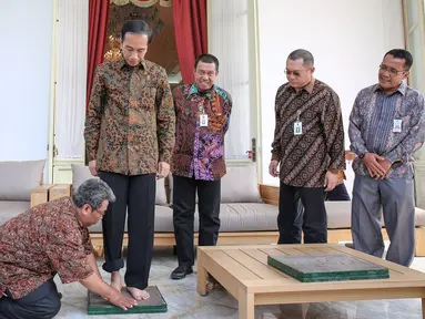 Presiden Joko Widodo berdiri untuk dicetak kakinya di Istana Merdeka, Jakarta, Selasa (13/10/2015). Cetakan tersebut akan diletakkan di Taman Pintar Yogyakarta. (Liputan6.com/Faizal Fanani)