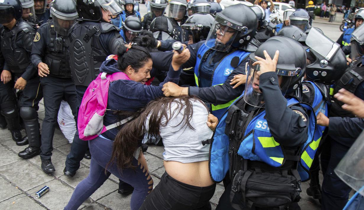 Fans saling dorong dengan polisi saat merayakan kemenangan Meksiko ats Jerman pada laga grup F Piala Dunia 2018 di Monumen Angel of Independence, Meksiko City (17/6/2018). Meksiko menang 1-0. (AP/Anthony Vazquez)