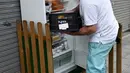 Pemilik restoran menyimpan makanan ke dalam kulkas di pinggir trotoar Galdakao, utara Spanyol, Senin (31/5). Warga setempat dan restoran bisa menaruh sisa makanan atau makanan tak terpakai ke dalam kulkas, dibanding harus membuangnya. (Ander GILLENEA/AFP)