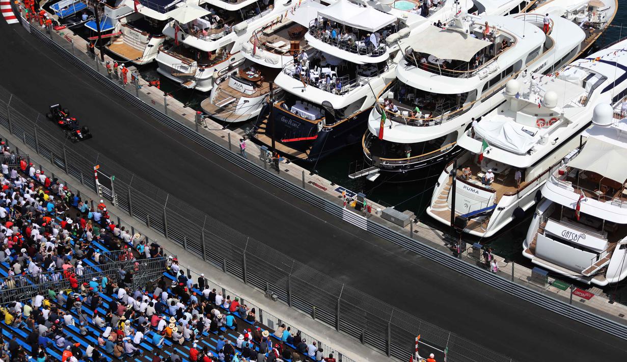 Pebalap McLaren, Jenson Button, melintas di depan deretan kapal pribadi dan tribun penonton pada latihan bebas F1 GP Monako, (26/5/2016). (AFP/Valery Hache)
