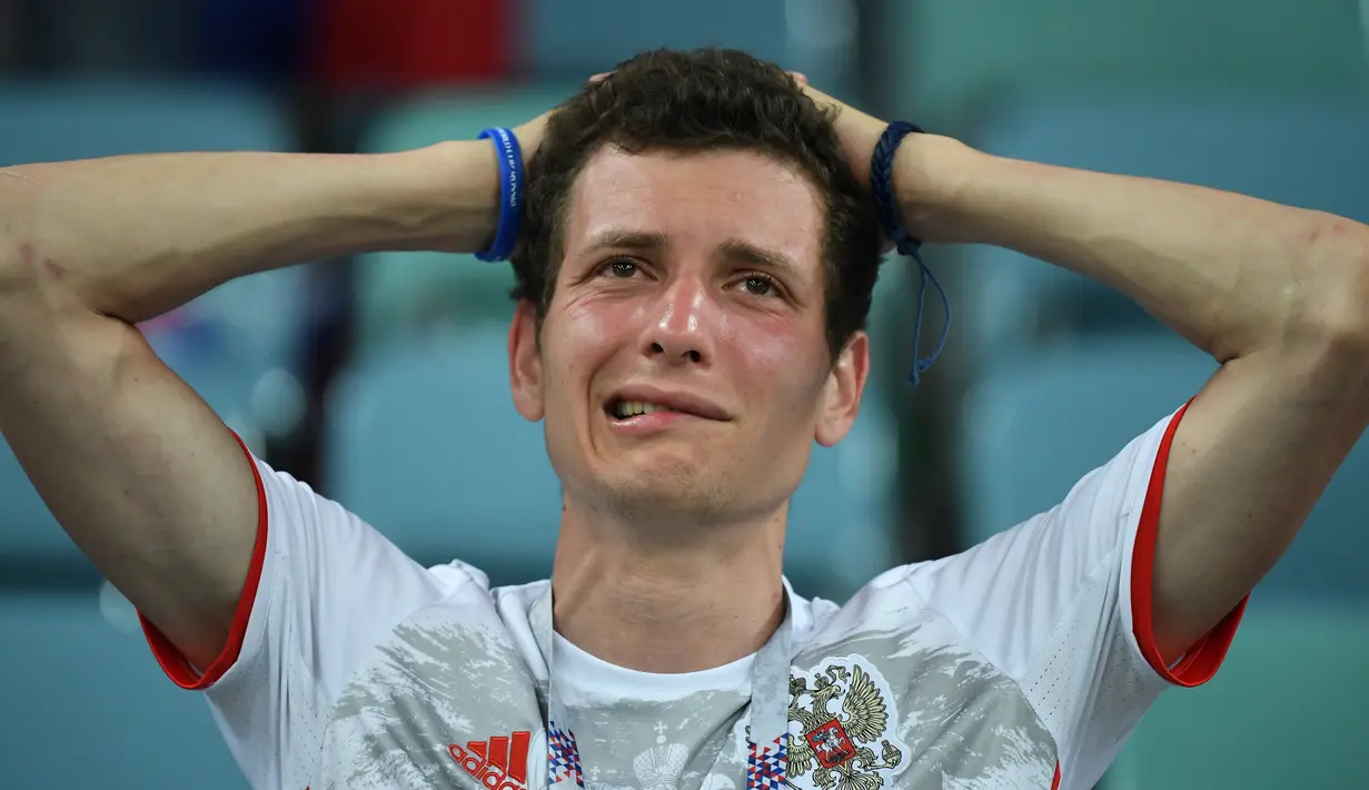 Seorang suporter Rusia terlihat kecewa setelah tim kesayangannya kalah dari Kroasia pada laga perempat final Piala Dunia 2018 di Stadion Olimpiade Fisht, Sabtu (7/7). Tuan rumah Rusia tumbang lewat adu penalti melawan Kroasia 3-4. (Kirill KUDRYAVTSEV/AFP)