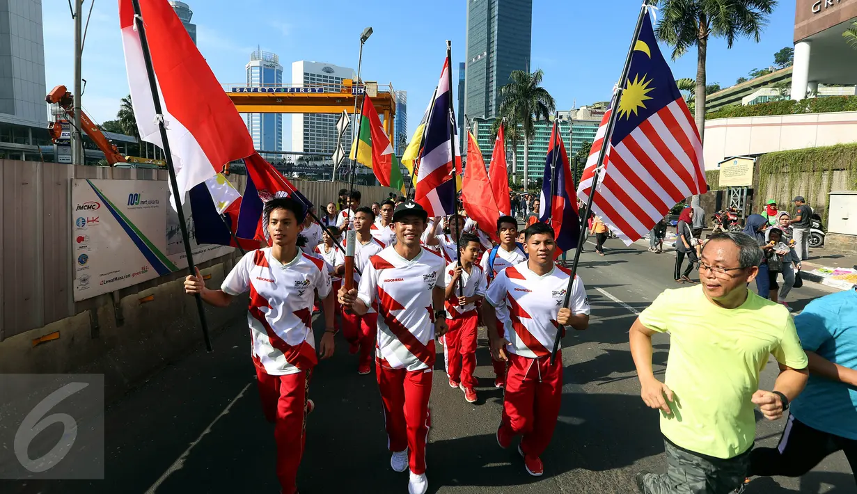 Sejumlah remaja membawa bendera negara-negara peserta Sea Games di Jakarta, Minggu (30/4). Kirab itu berlangsung guna menyambut Sea Games Kuala Lumpur 2017. (Liputan6.com/Johan Tallo)