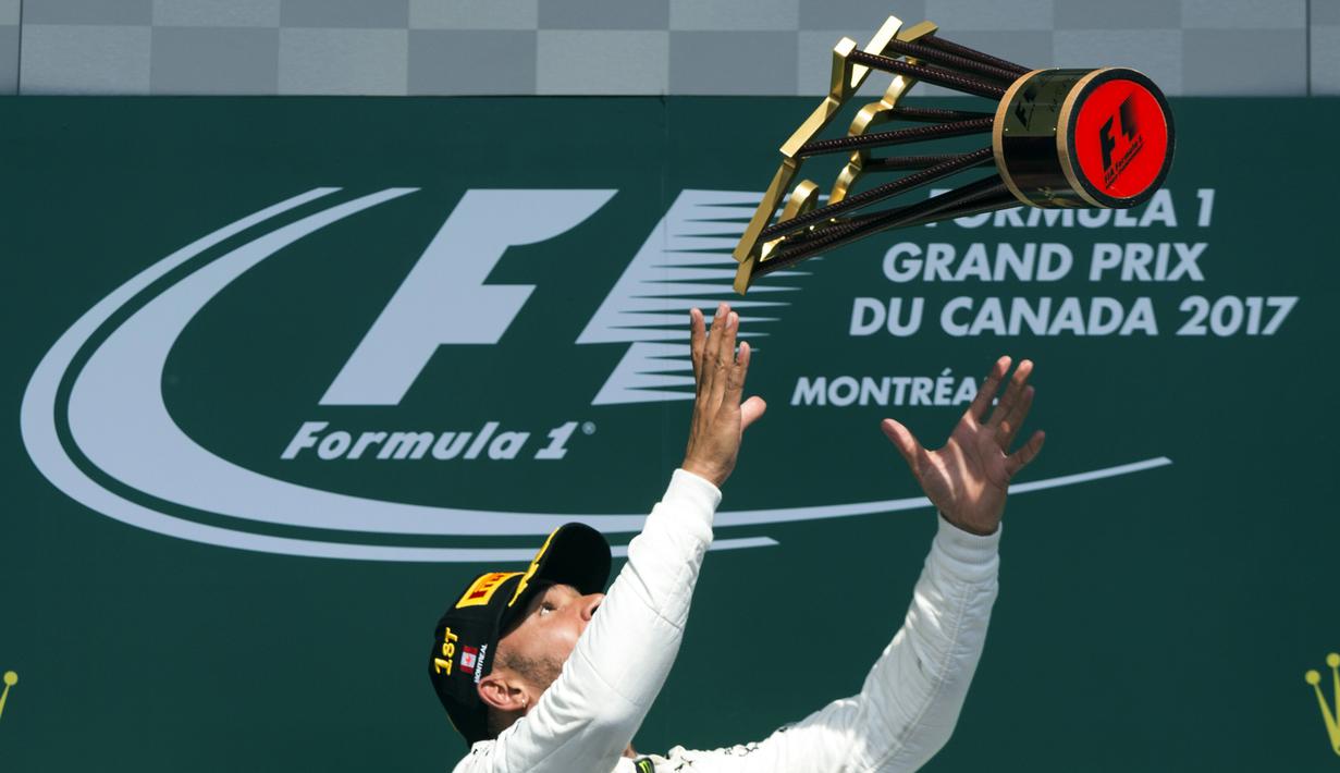 Lewis Hamilton melempar trofi juara setelah menang  pada ajang Formula One Canadian Grand Prix di Montreal, Canada, (11/6/2017).  (Paul Chiasson/The Canadian Press via AP)