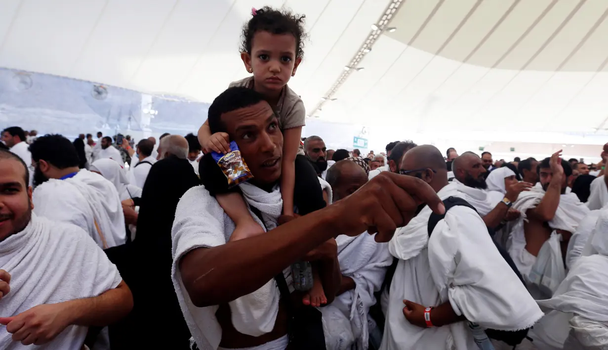 Jemaah haji melempar jumrah sambil menggendong anak saat ibadah haji di Mina, Arab Saudi (12/09). Lempar jumrah dapat dimaknai melontarkan sifat trilogi thaghut (pendurka Allah) yakni Qarun, Bal’am, dan Fir’aun. (REUTERS/Ahmed Jadallah)