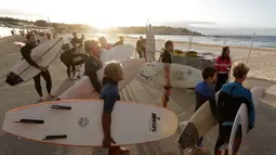 Peselancar menunggu petugas membuka Pantai Bondi saat pembatasan sosial mulai dilonggarkan di Sydney, Selasa, (28/4/2020). Australia mencatat penurunan Covid-19 secara drastis. Sejumlah pembatasan sosial mulai dilonggarkan. Salah satunya pembukaan kembali Pantai Bondi. (AP Photo/Rick Rycroft)