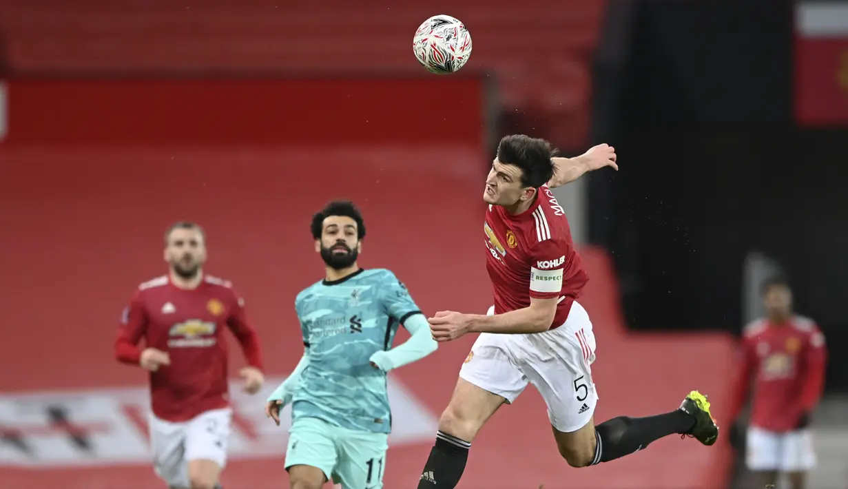 Pemain Manchester United, Harry Maguire (kanan) berusaha menghalau bola pada laga babak keempat FA Cup 2020-21 di Old Trafford, Senin (25/01/2021). (Foto: AP/Pool/Laurence Griffiths)