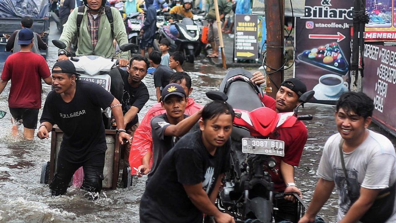 Warga menarik gerobak yang mengangkut sepeda motor saat banjir parah merendam jalur penghubung Jakarta-Tangerang di kawasan Joglo, Jakarta, Jumat (22/3/2024). Liputan6.com/Angga Yuniar