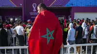Seorang pria berbalut bendera Maroko mengantre dengan suporter di luar Stadion Al Janoub di Wakrah, dengan harapan mendapatkan tiket pertandingan sepak bola semifinal Piala Dunia 2022 antara Prancis vs Maroko, Selasa (13/12/2022). Partai hidup mati akan tersaji antara timnas Prancis melawan Maroko pada babak semifinal Piala Dunia 2022 di Stadion Al Bayt, Kamis (15/12) dini hari WIB. (AP Photo/Francisco Seco)