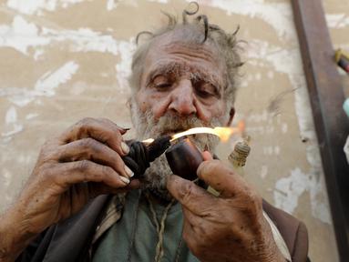 Georges Gerges, yang dijuluki "Kapten" menyalakan rokok saat duduk di sudut jalan kawasan industri Dora di pinggiran utara Beirut, Rabu (8/11). Gerges dulunya adalah ilmuwan dan dosen di salah satu universitas paling bergengsi di Lebanon. (JOSEPH EID/AFP)