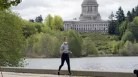 Seseorang memakai masker saat jogging di dekat Capitol di Olympia, Washington, Selasa (27/4/2021). Warga Amerika Serikat (AS) yang telah menerima vaksin COVID-19 tidak lagi diwajibkan mengenakan masker saat berada di luar ruangan jika tidak ada kerumuman. (AP Photo/Ted S. Warren)