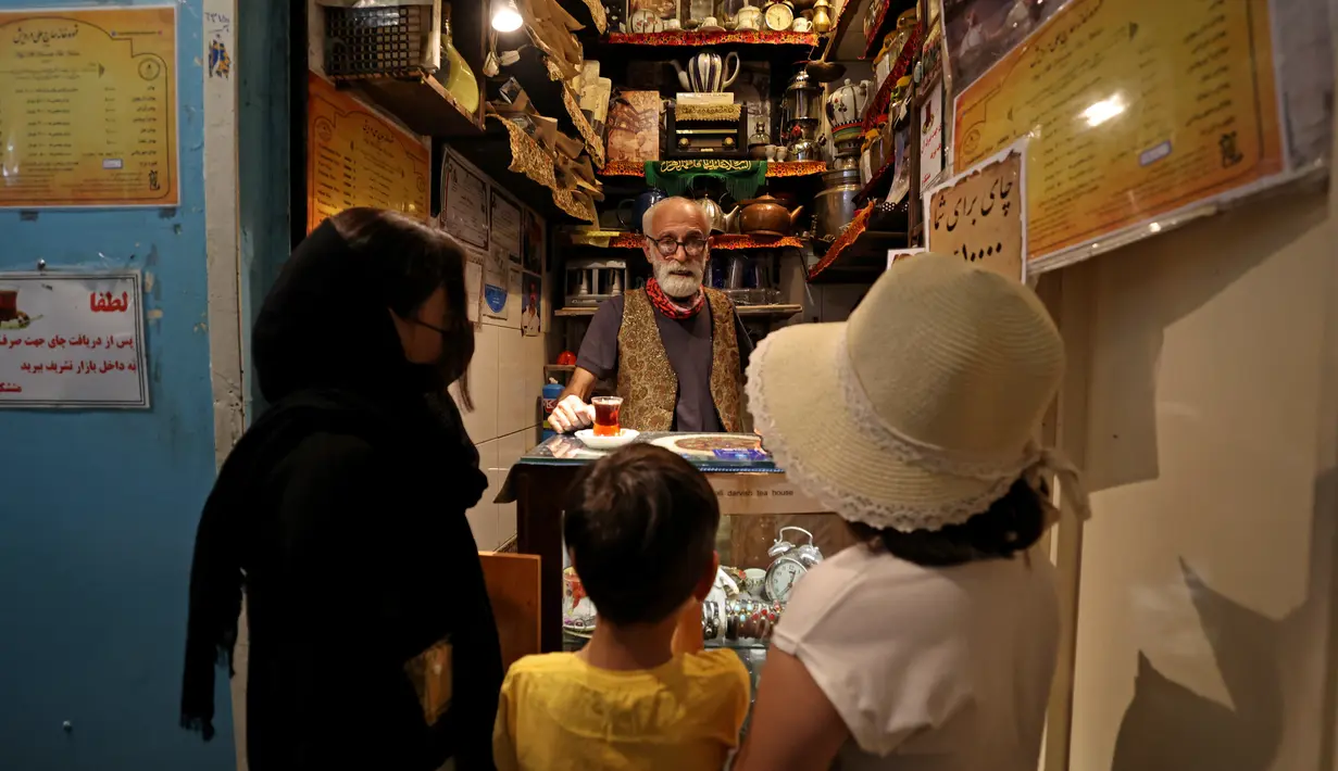Pemilik Kazem Mabhutian (63) menyajikan teh di kedai teh terkecil dan tertua di gang Grand Bazaar di ibukota Iran, Teheran (20/9/2021).  Di sela-sela menuangkan segelas teh untuk pelanggannya, Kazem memberi tahu kisah seabad tentang Rumah Teh Haj Ali Darvish dengan bangga. (AFP/Atta Kenare)