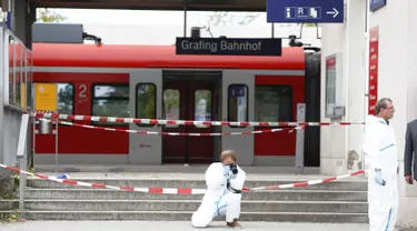 Polisi mengambil gambar di lokasi penyerangan di stasiun kereta komuter S-Bah di Grafing, kota di Munich, Jerman selatan, Selasa (10/5). Penikaman yang dilakukan seorang pria berusia 27 tahun itu dilaporkan menewaskan satu orang. (REUTERS/Michaela Rehle)