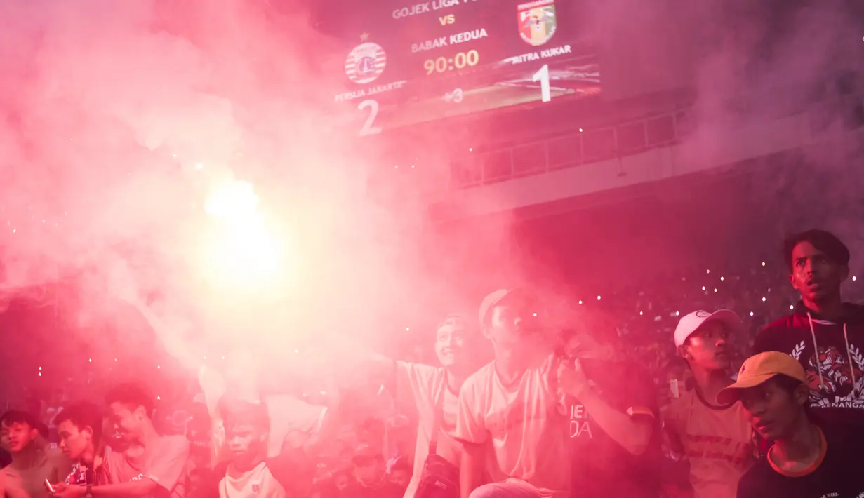 Suporter Persija Jakarta, The Jakmania, menyalahkan flare saat merayakan gelar juara usai mengalahkan Mitra Kukar pada laga Liga 1 di SUGBK, Jakarta, Minggu (9/12). Persija menang 2-1 atas Mitra. (Bola.com/Vitalis Yogi Trisna)