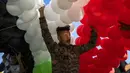 Seorang pendukung Presiden Suriah Bashar Assad bersiap melepas ratusan balon berwarna bendera Suriah pada pertemuan di Omayyid Square, Damaskus, Suriah, Minggu (23/5/2021). Pemilihan presiden di negara yang dilanda perang itu akan diadakan pada 26 Mei. (AP Photo/Hassan Ammar)