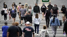 Pejalan kaki dengan masker dan tanpa masker berjalan di sepanjang Las Vegas Strip, di Las Vegas Selasa (27/4/2021). Warga Amerika Serikat (AS) yang telah menerima vaksin COVID-19 tidak lagi diwajibkan mengenakan masker saat berada di luar ruangan jika tidak ada kerumuman. (AP Photo/John Locher)