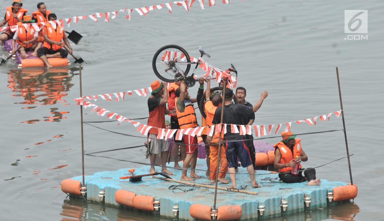 Tim pemenang mengangkat sepeda sebagai hadiah usai menjuarai lomba dayung di Kanal Banjir Timur, Jakarta, Sabtu (17/8/2019). Dalam memeriahkan HUT ke-74 RI, petugas UPK Badan Air DLH Kecamatan Duren Sawit menggelar sejumlah perlombaan, salah satunya lomba dayung. (merdeka.com/ Iqbal S. Nugroho)