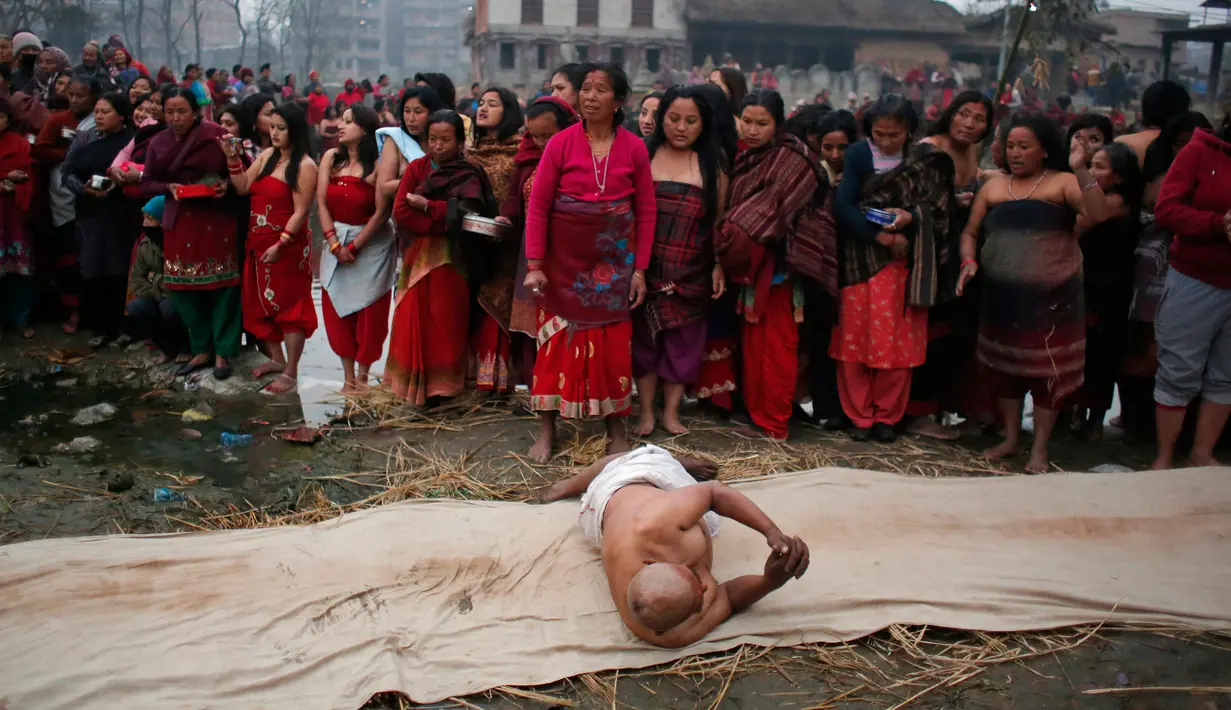 Seorang pria Hindu Nepal berguling di tepi sungai Hanumante saat festival Madhav Narayan di Bhaktapur, Nepal (31/1). Dalam ritual ini, wanita yang belum menikah berdoa untuk mendapatkan suami yang baik. (AP Photo / Niranjan Shrestha)
