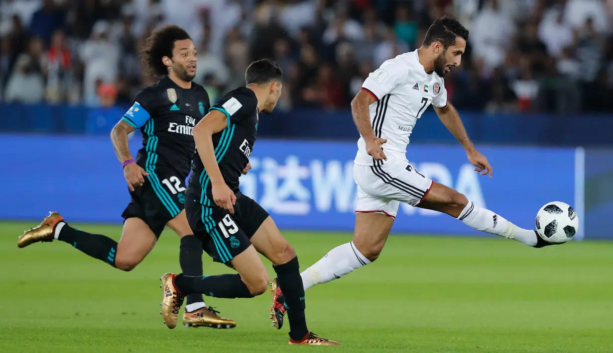 Pemain Al Jazira, Ali Mabkhout saat menendang bola dari kawalan dua pemain Real Madrid pada semifinal Piala Dunia Antarklub di Syekh Zayed Sports City Stadium, (14/12). Madrid menang 2-1 atas Al Jazira. (AP Photo/Hassan Ammar)