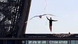 Seniman trapeze, Nathan Paulin berjalan di seutas tali dari Menara Eiffel menuju alun-alun Trocadero, Paris, 9 Desember 2017. Aksi itu bagian dari Telethon ke-31 untuk menggalang dana bagi kegiatan penelitian penyakit langka. (JACQUES DEMARTHON/AFP)