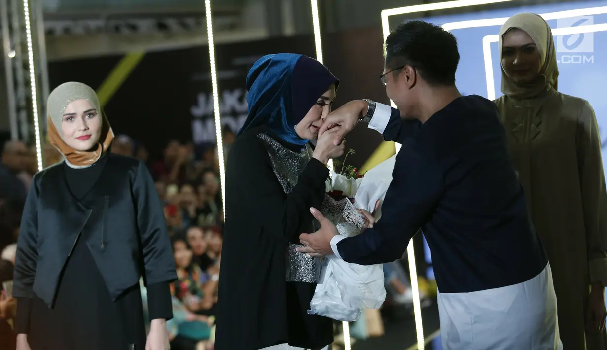 Fenita Arie mencium tangan suaminya Arie Untung saat menampilkan busana L.tru X Fenita Arie dalam ajang Jakarta Modest  Fashion Week, di Gandaria City, Jakarta, Jumat, (27/7). (Kapanlagi.com/Agus Apriyanto)