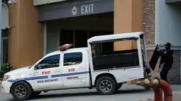 Petugas kepolisian memasukkan tameng pelindung ke dalam kendaraan di luar hotel Resorts World Manila, Filipina, Jumat (2/6). Seorang pria bersenjata ditemukan bunuh diri usai menyerang ruang kasino dengan beberapa kali tembakan. (AP Photo/Aaron Favila)